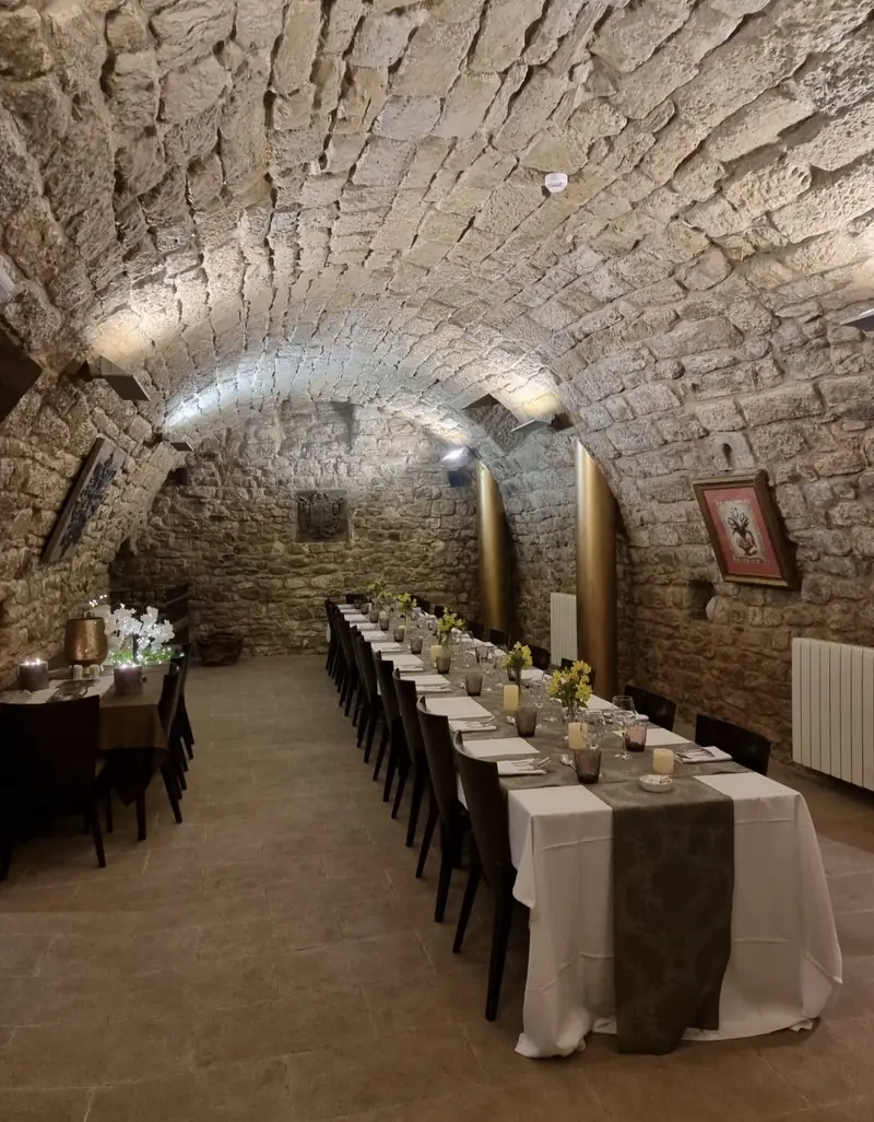 La bodega: una sala de piedra con bóveda de cañón y una mesa larga preparada con flores amarillas